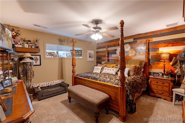 carpeted bedroom with ceiling fan and wood walls