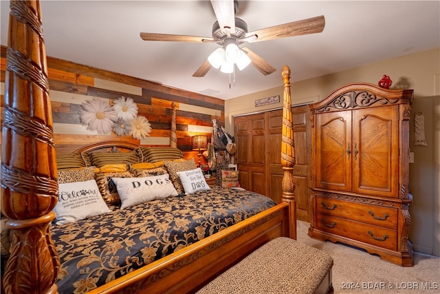 bedroom featuring a closet, ceiling fan, light carpet, and wood walls