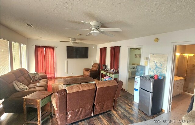 living room featuring ceiling fan, dark wood-type flooring, and a textured ceiling