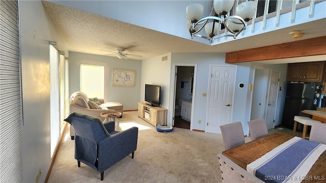 living room featuring a textured ceiling, ceiling fan with notable chandelier, and light colored carpet