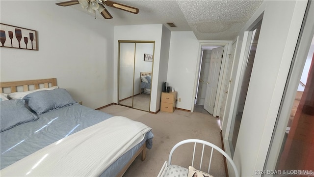 bedroom featuring ceiling fan, light carpet, and a textured ceiling