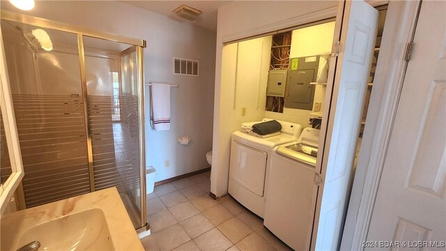 washroom featuring washing machine and dryer, sink, and light tile patterned floors