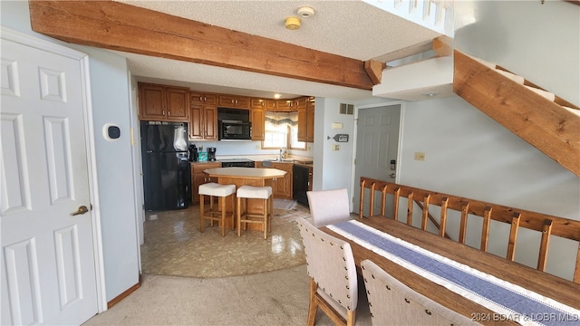 kitchen featuring a kitchen breakfast bar, a textured ceiling, a kitchen island, and black appliances