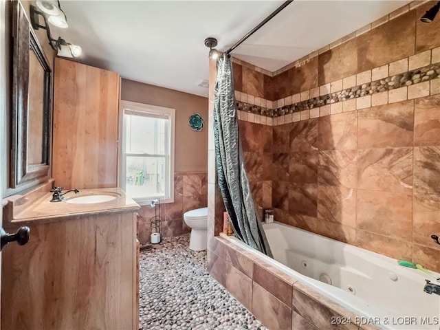 full bathroom featuring toilet, shower / bath combo, vanity, and tile walls