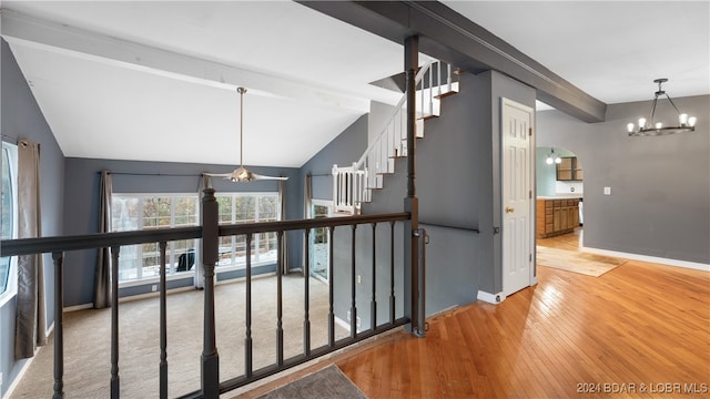 corridor featuring hardwood / wood-style floors, lofted ceiling with beams, and a chandelier