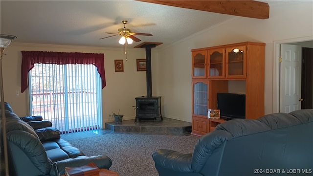 living room featuring carpet flooring, vaulted ceiling with beams, a wood stove, ceiling fan, and ornamental molding