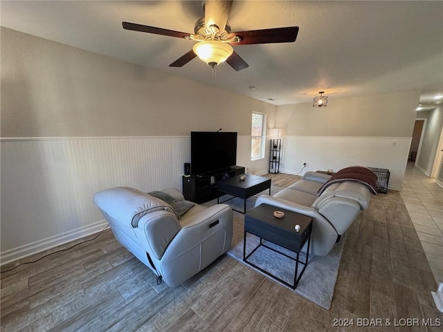 living room with baseboards, ceiling fan, wood finished floors, and a wainscoted wall
