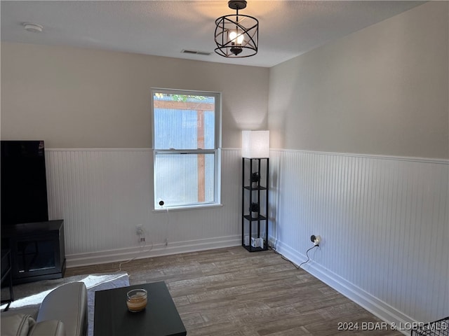 empty room with a notable chandelier, a textured ceiling, and hardwood / wood-style floors