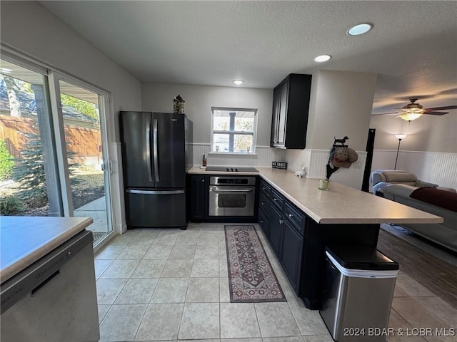 kitchen with a peninsula, ceiling fan, light countertops, a textured ceiling, and appliances with stainless steel finishes