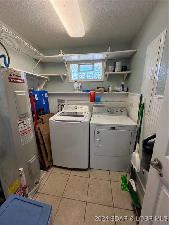 laundry area with water heater, laundry area, washing machine and dryer, and a textured ceiling