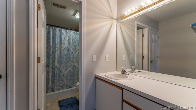 bathroom with vanity, toilet, a textured ceiling, and curtained shower