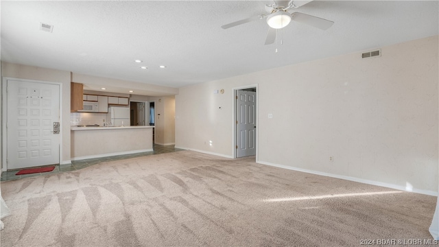 unfurnished living room with light colored carpet and ceiling fan