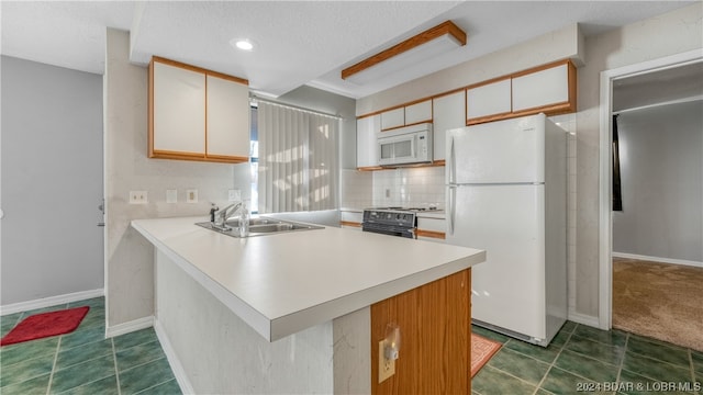 kitchen featuring white appliances, dark tile patterned flooring, sink, kitchen peninsula, and white cabinets