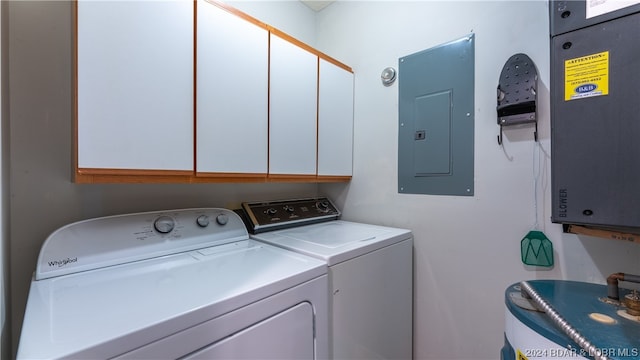 washroom with cabinets, water heater, electric panel, and washing machine and dryer