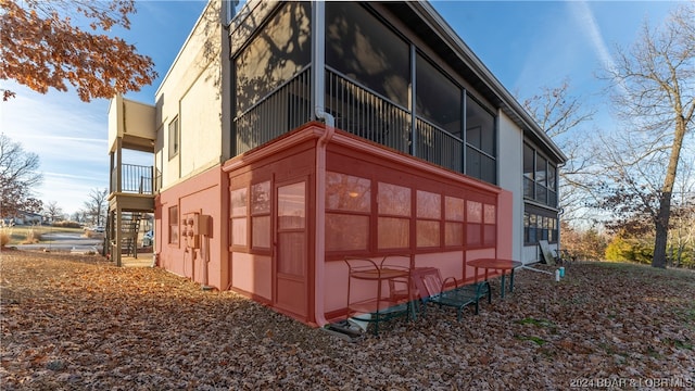 view of property exterior with a sunroom and a balcony