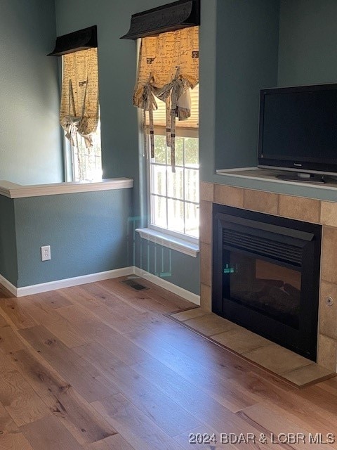 unfurnished living room featuring light hardwood / wood-style flooring and a tile fireplace