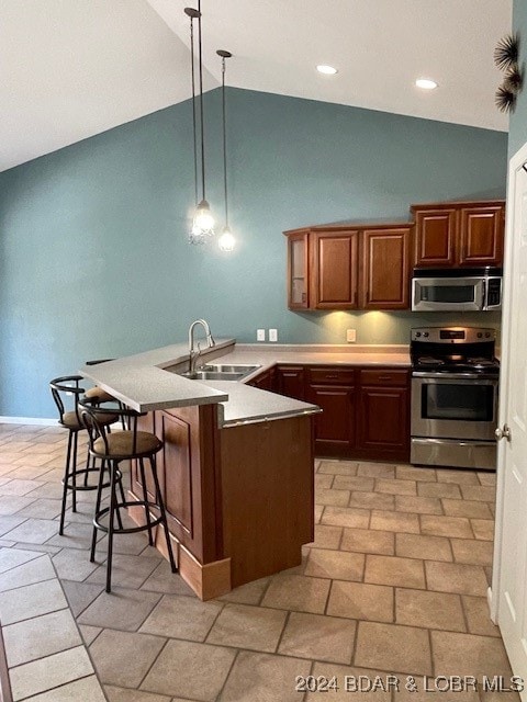 kitchen featuring a breakfast bar area, kitchen peninsula, sink, decorative light fixtures, and appliances with stainless steel finishes