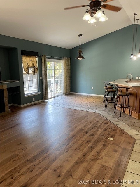 dining room with light hardwood / wood-style floors, ceiling fan, sink, and vaulted ceiling