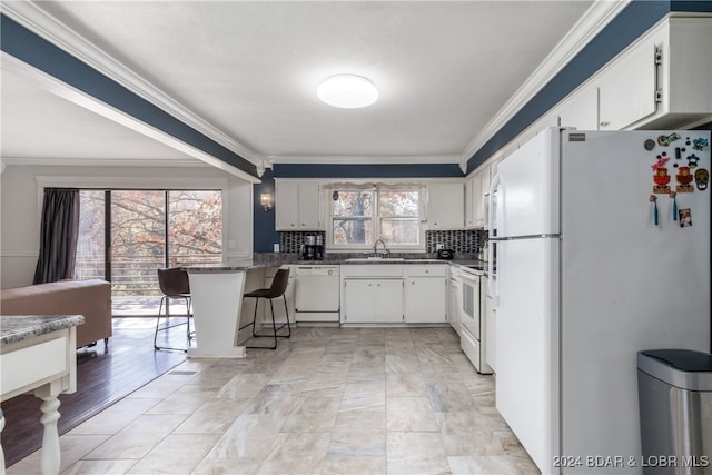 kitchen with white cabinetry, plenty of natural light, and white appliances