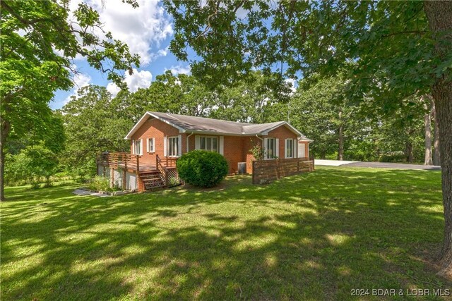 24950 State Rd A Rd, Richland, MO 65556 - view of front facade featuring a deck, brick siding, a front yard, and view of scattered trees