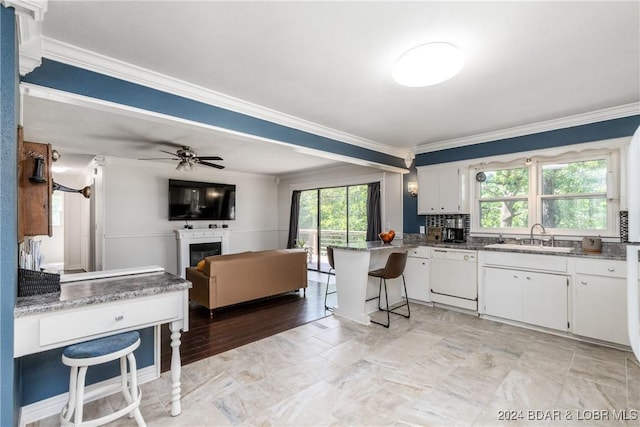 24950 State Rd A Rd, Richland, MO 65556 - kitchen featuring white dishwasher, crown molding, a kitchen breakfast bar, a glass covered fireplace, and ceiling fan