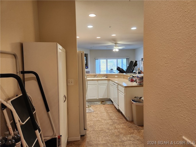 kitchen with white cabinetry, kitchen peninsula, refrigerator, light tile patterned floors, and dishwasher