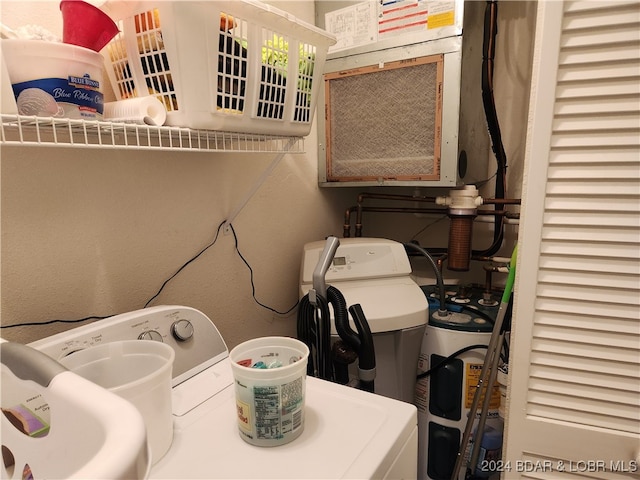 clothes washing area with water heater and washer and clothes dryer