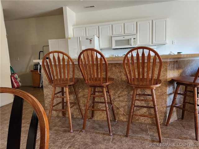 bar featuring white cabinets and dark tile patterned floors