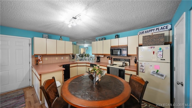 kitchen with backsplash, black appliances, a textured ceiling, and light hardwood / wood-style floors