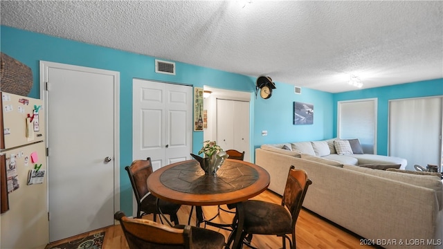 dining area with a textured ceiling and light wood-type flooring