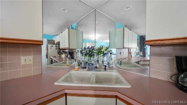 kitchen featuring white cabinetry, decorative backsplash, a textured ceiling, and sink