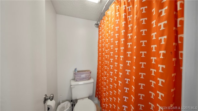 bathroom with toilet, a textured ceiling, and a shower with curtain