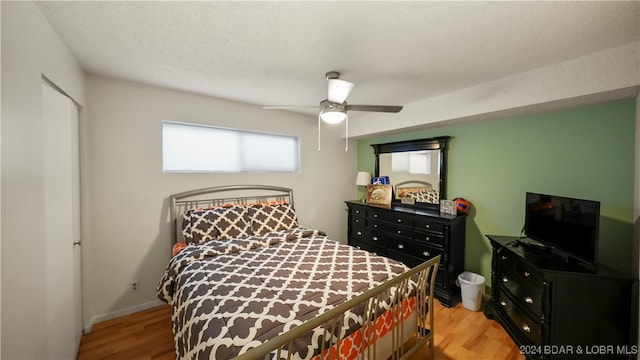 bedroom featuring light hardwood / wood-style flooring, a textured ceiling, a closet, and ceiling fan