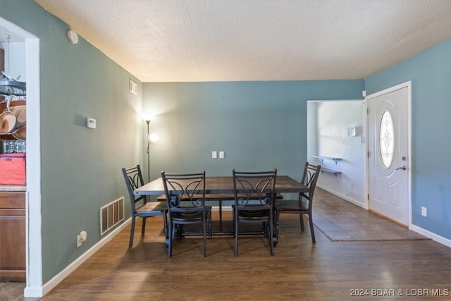 dining room featuring dark wood-type flooring and a textured ceiling