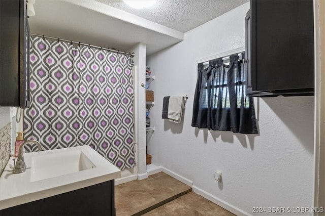 bathroom with vanity, a textured ceiling, and tile patterned floors