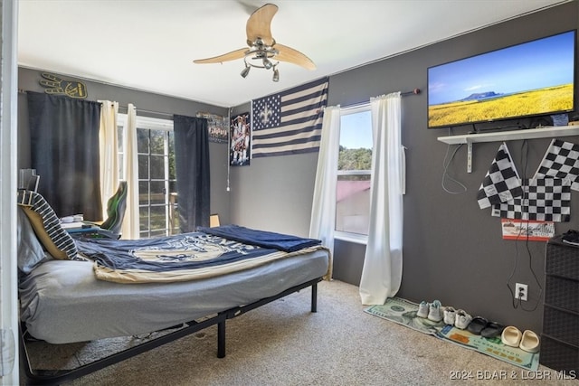 bedroom featuring ceiling fan, multiple windows, and carpet floors