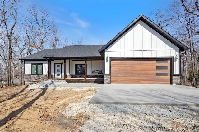 modern inspired farmhouse featuring stone siding, driveway, and a garage