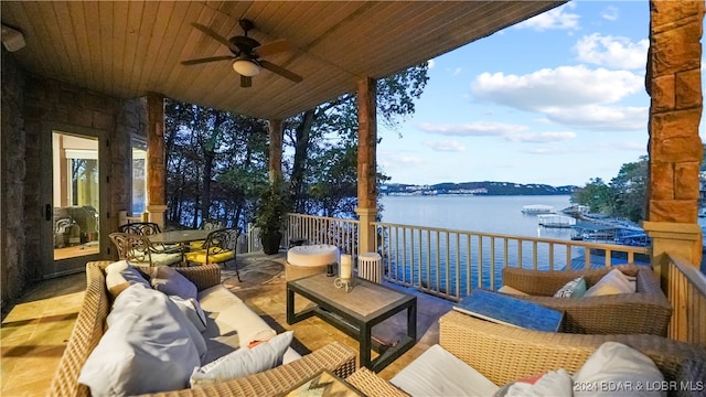 wooden terrace with outdoor lounge area, ceiling fan, and a water view