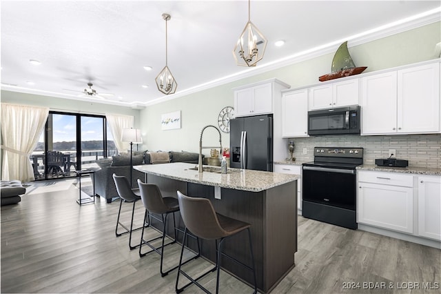 kitchen with stainless steel fridge, range with electric stovetop, white cabinetry, pendant lighting, and a kitchen island with sink