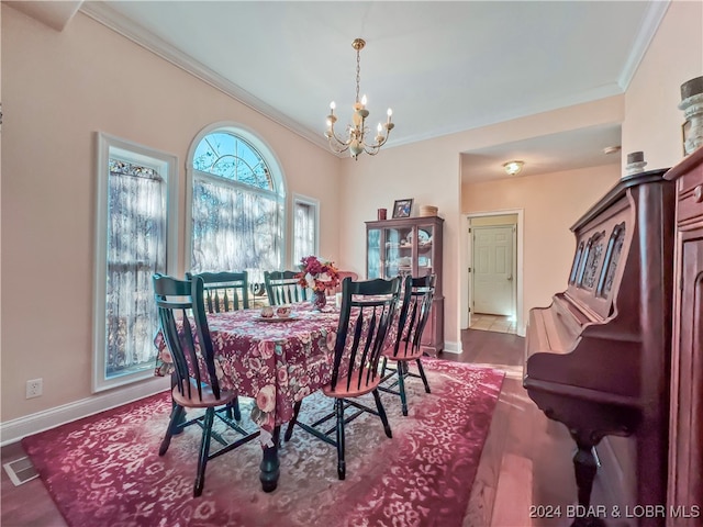 dining room with ornamental molding, wood-type flooring, and an inviting chandelier