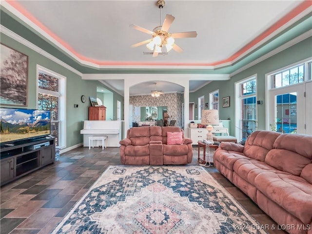 293 Windsong, Camdenton, MO 65020 - living room with ceiling fan, a tray ceiling, arched walkways, crown molding, and dark stone finish flooring