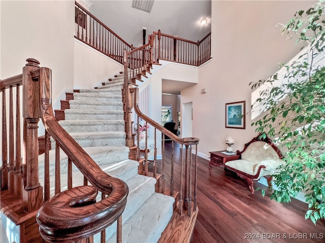 stairway with hardwood / wood-style floors and a high ceiling