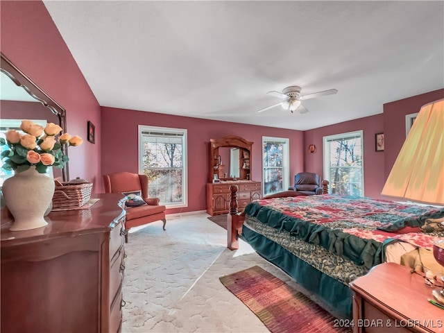 bedroom with light colored carpet, multiple windows, and ceiling fan