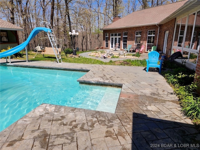 view of swimming pool featuring a patio area, french doors, and a water slide