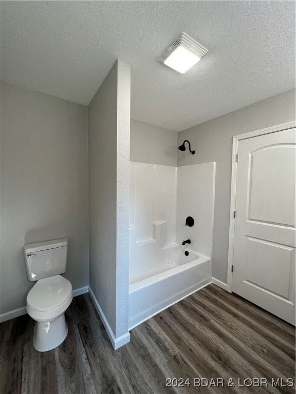 bathroom with hardwood / wood-style floors, a textured ceiling, toilet, and  shower combination