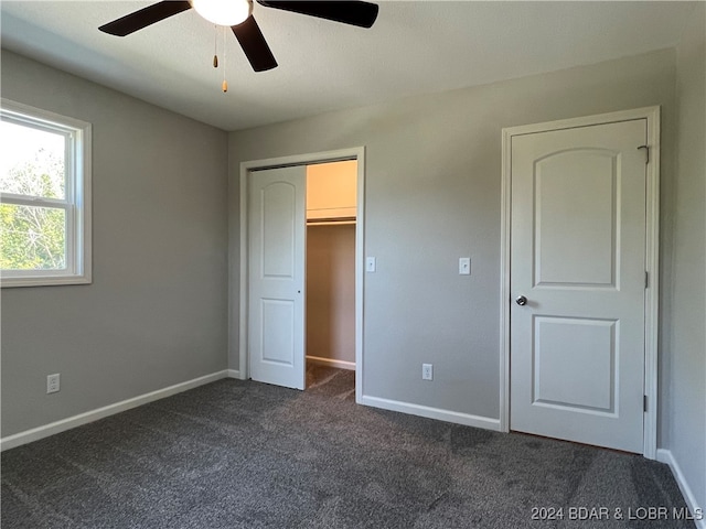 unfurnished bedroom featuring ceiling fan, dark colored carpet, and a closet