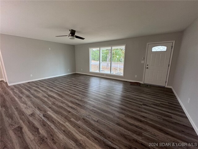 unfurnished living room with dark hardwood / wood-style flooring and ceiling fan