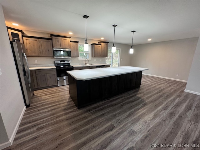 kitchen featuring a kitchen island, appliances with stainless steel finishes, hanging light fixtures, sink, and dark wood-type flooring