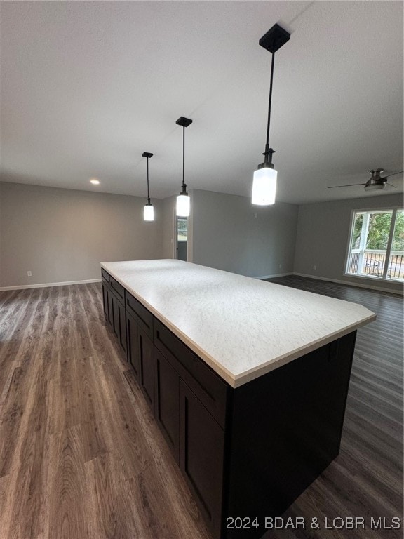 kitchen featuring dark wood-type flooring, ceiling fan, decorative light fixtures, and a kitchen island