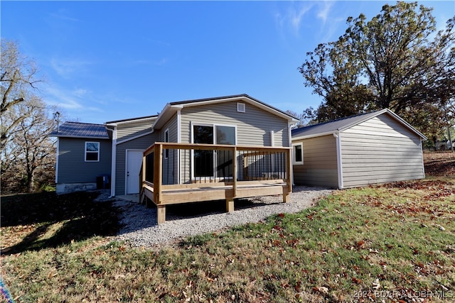 rear view of property featuring an outbuilding, a lawn, and a deck